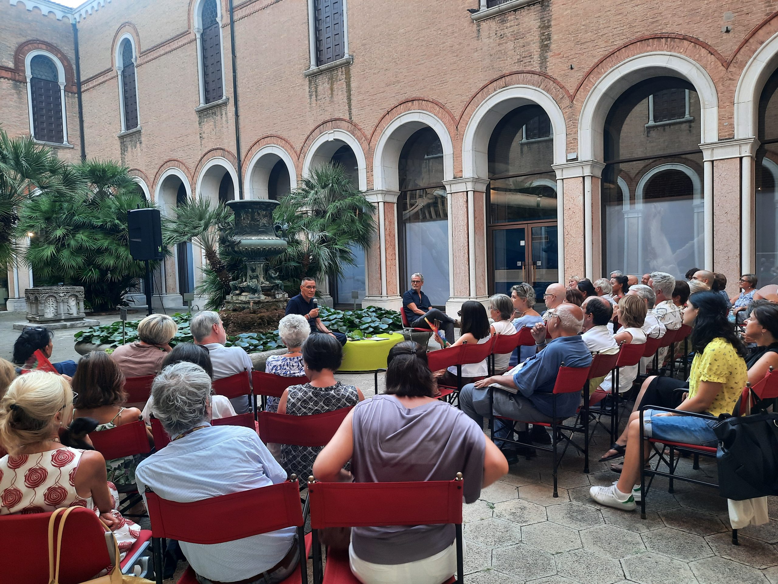 Foto persone sedute nel giardino del Museo durante una presentazione